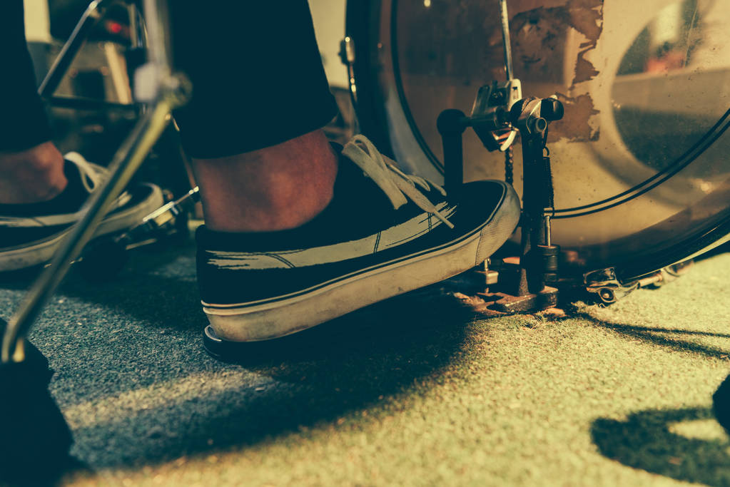 περικοπεί άποψη για τον άνθρωπο σε πάνινα παπούτσια πιέζοντας το πεντάλ μπάσα  - Φωτογραφία, εικόνα
