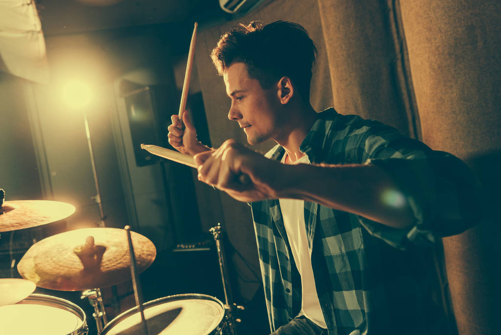 красивий барабанщик тримає барабанні палички і грає на барабанах
 - Фото, зображення