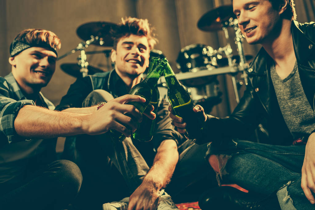 selectieve aandacht van vrolijke vrienden rammelende glazen flessen bier  - Foto, afbeelding