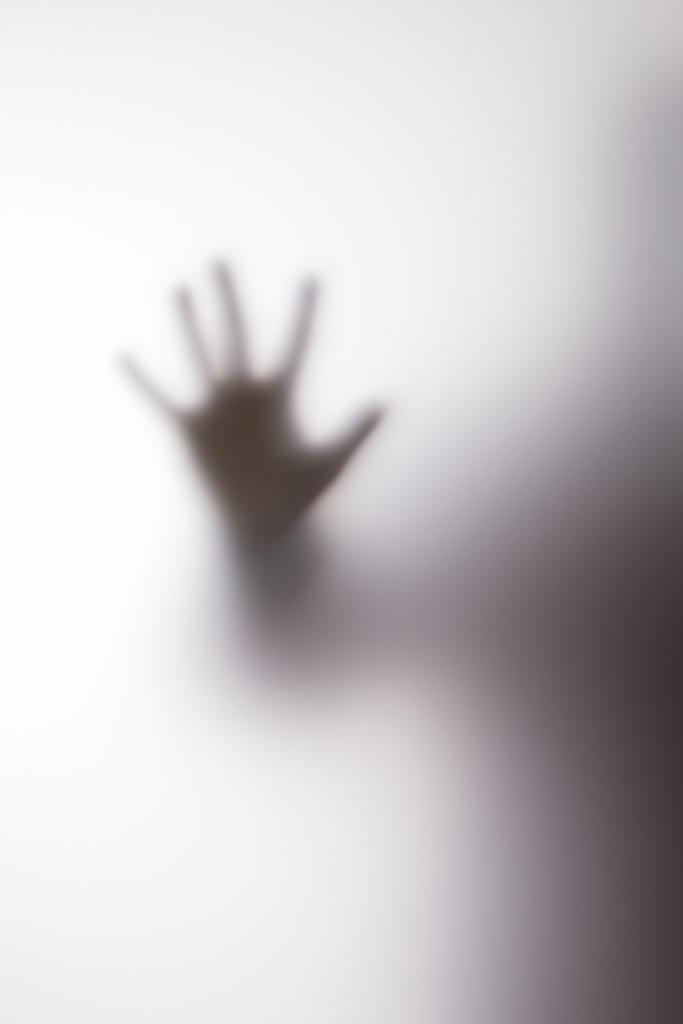 Silueta borrosa de persona tocando vidrio con la mano
 - Foto, imagen