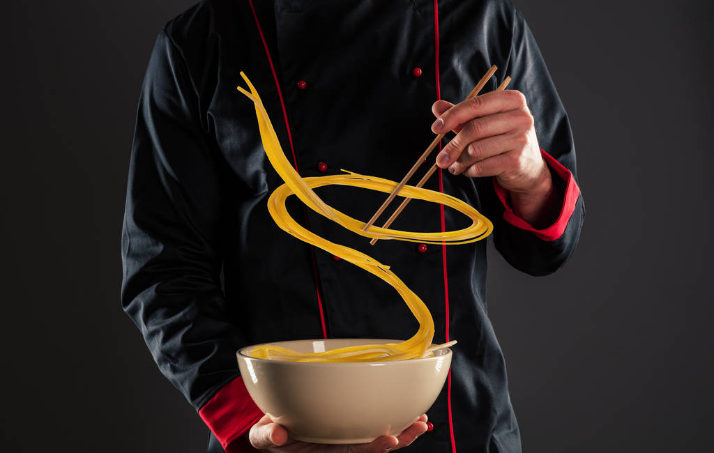 Master chef holding chopsticks with flying noodles - Photo, Image