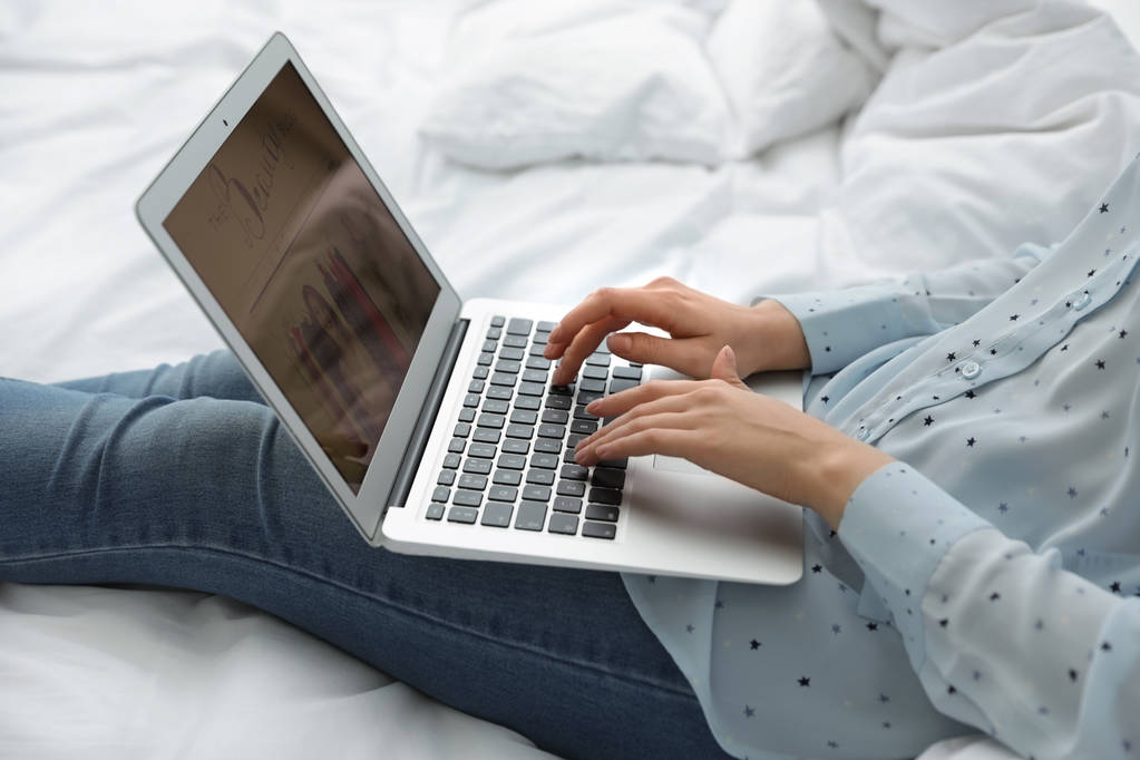 Woman holding laptop with open beauty blogger site on bed, closeup - Photo, Image