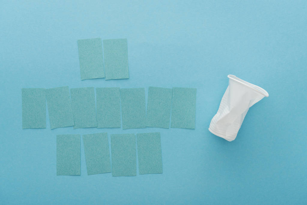 top view of white plastic cup and empty sticky notes on blue background  - Photo, Image