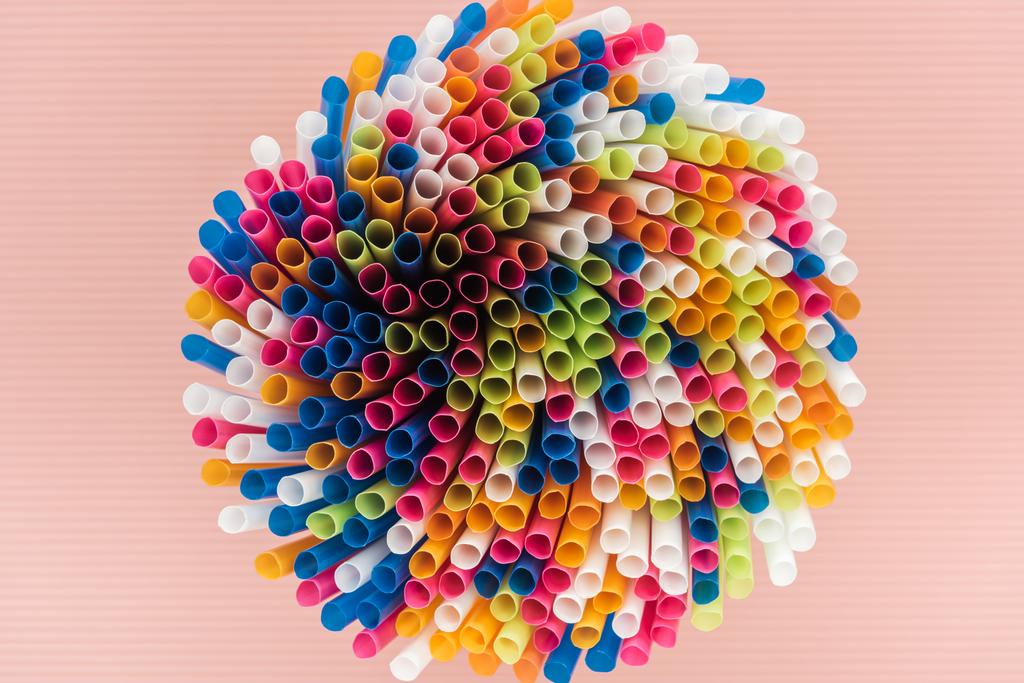 κάτοψη του πολύχρωμο και φωτεινό πλαστικά καλαμάκια που απομονώνονται σε ροζ - Φωτογραφία, εικόνα