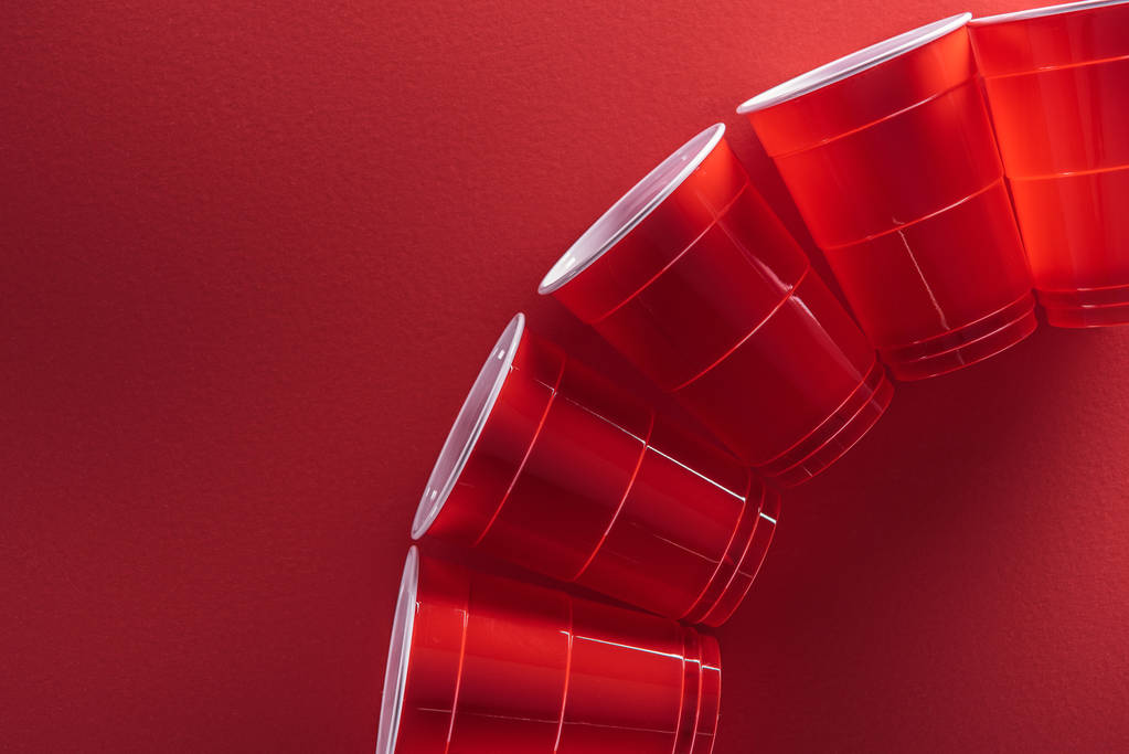 tendido plano con copas de plástico brillantes y coloridos sobre fondo rojo con espacio de copia
  - Foto, Imagen