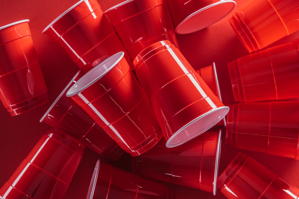 вид зверху яскравих і барвистих пластикових чашок на червоному тлі
  - Фото, зображення