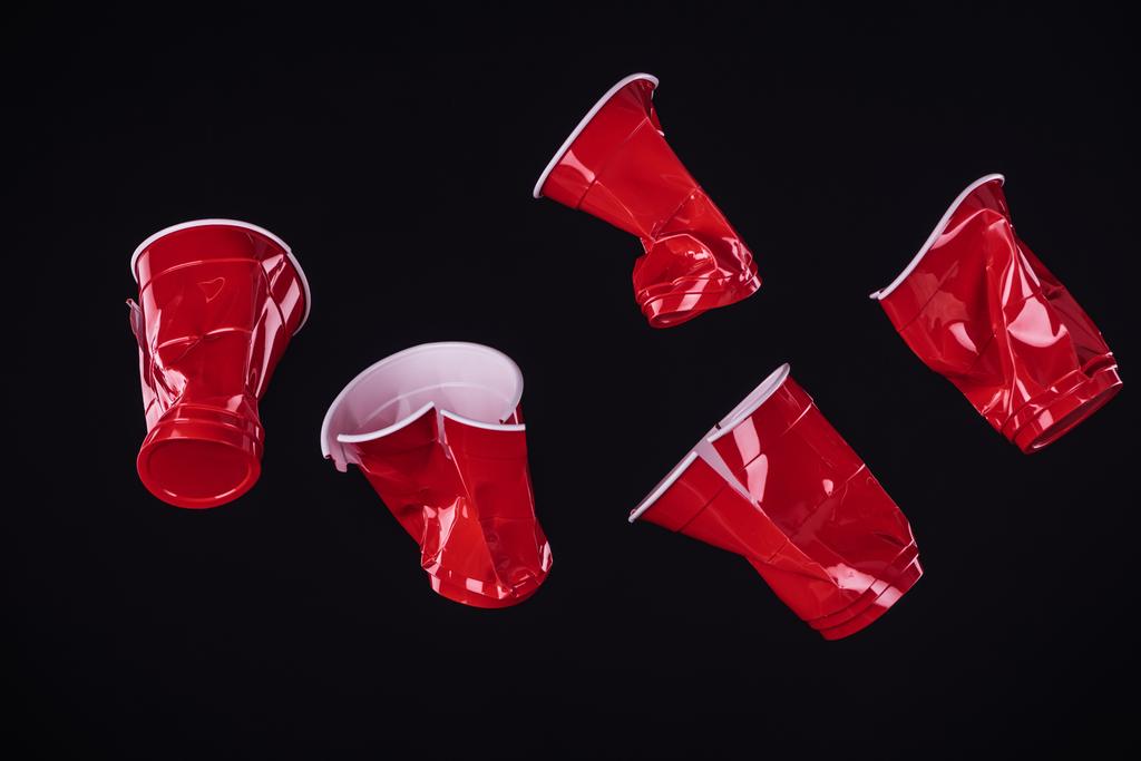 vista superior de brillantes y coloridas copas de plástico rojo aisladas en negro con espacio de copia
  - Foto, Imagen