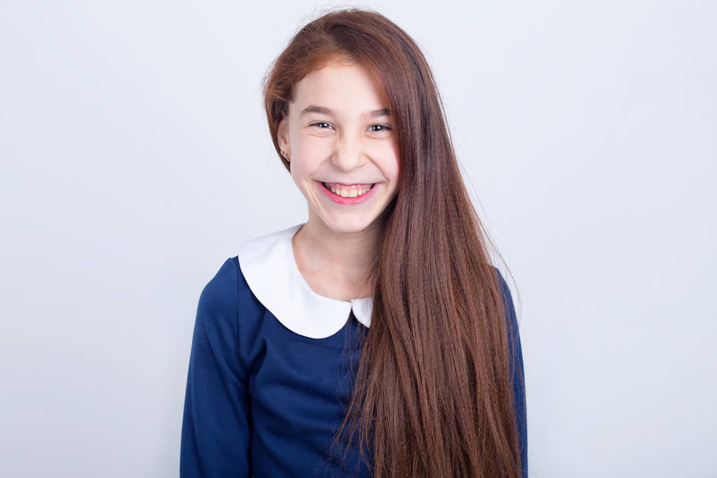 Porträt eines jungen lächelnden Mädchens auf hellem Hintergrund. rothaarige Schulmädchen. - Foto, Bild