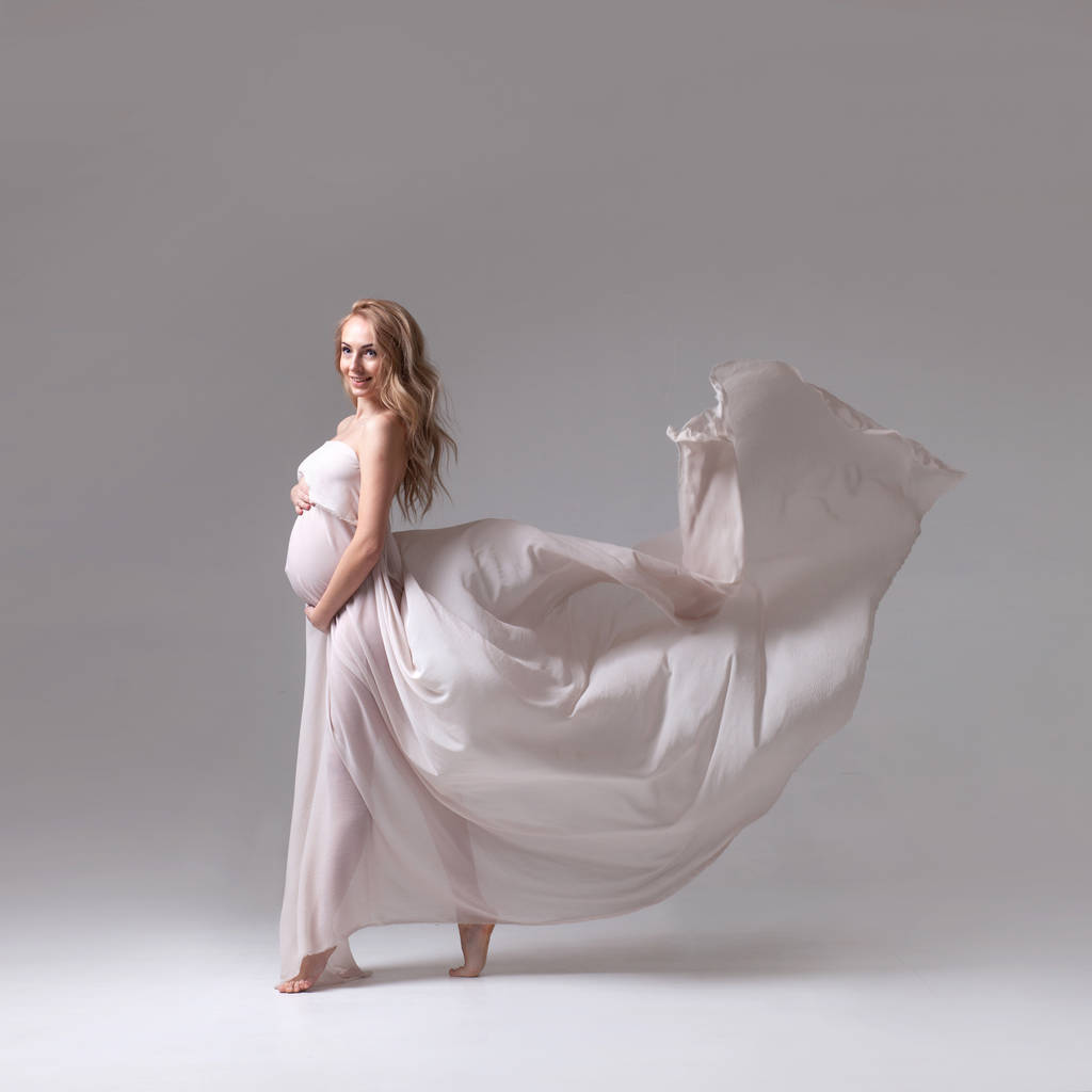 κομψό έγκυος γυναίκα σε μια λευκή που φέρουν φόρεμα - Φωτογραφία, εικόνα