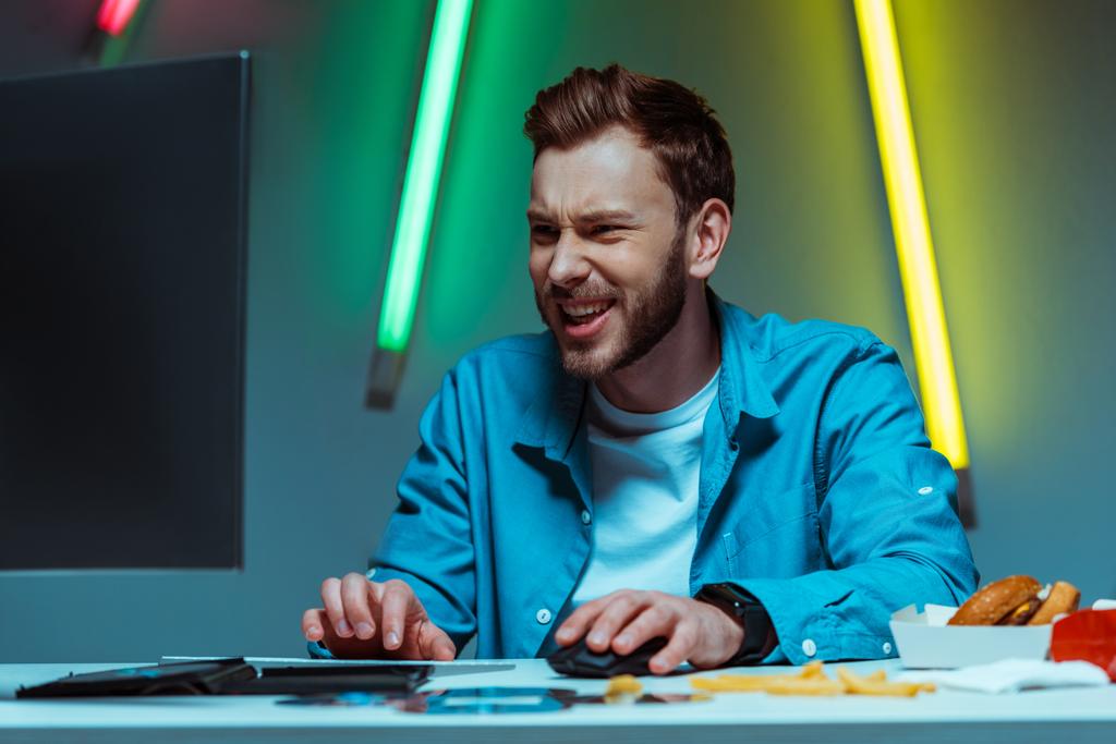 homem bonito e feliz jogando videogame com mouse e teclado de computador
 - Foto, Imagem
