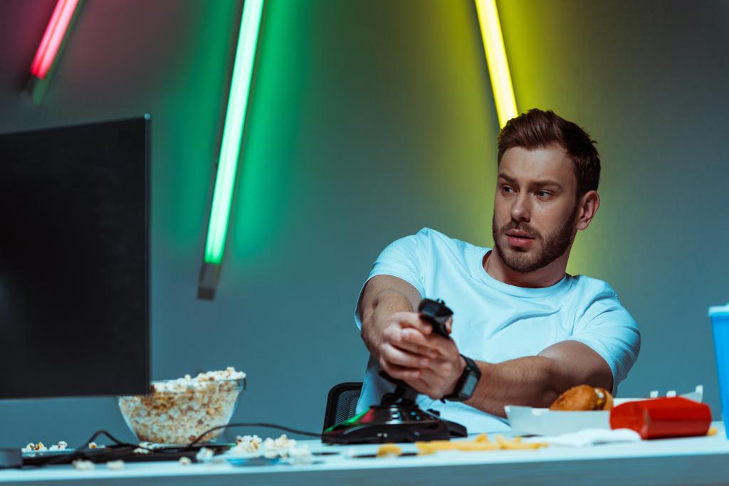 knappe en goed uitziende Cyber Sportsman spelen van video game met joystick - Foto, afbeelding