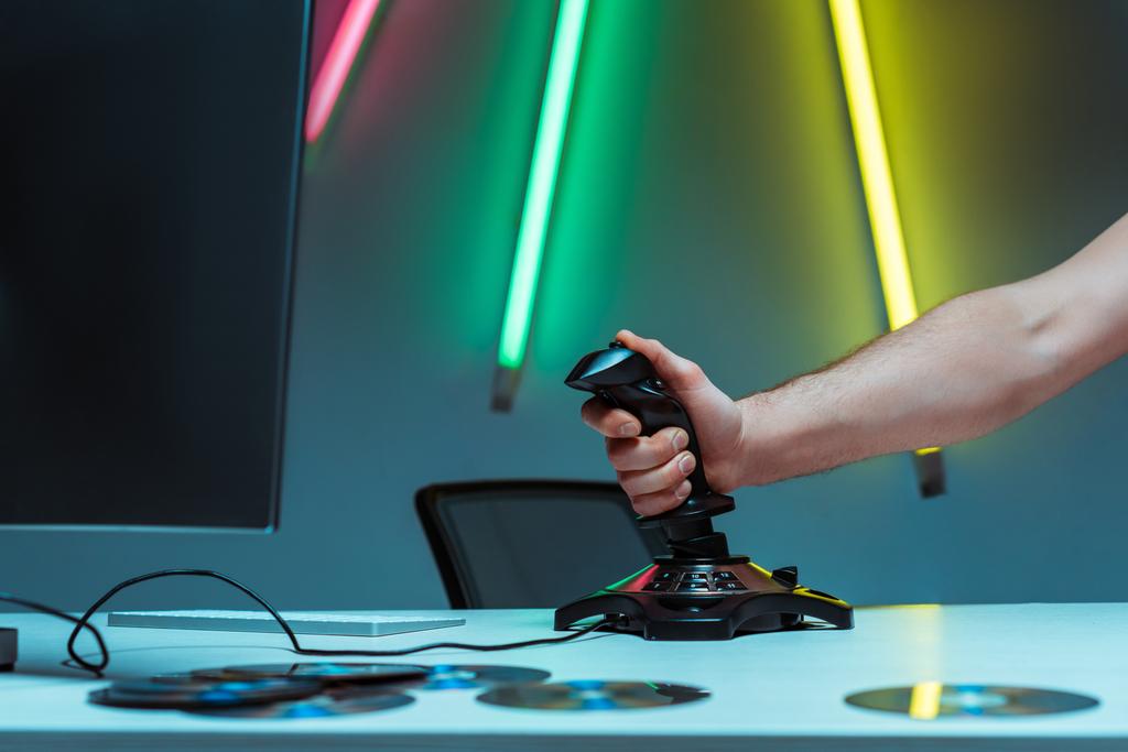 gedeeltelijke weergave van de mens Holding joystick op tafel in appartement - Foto, afbeelding