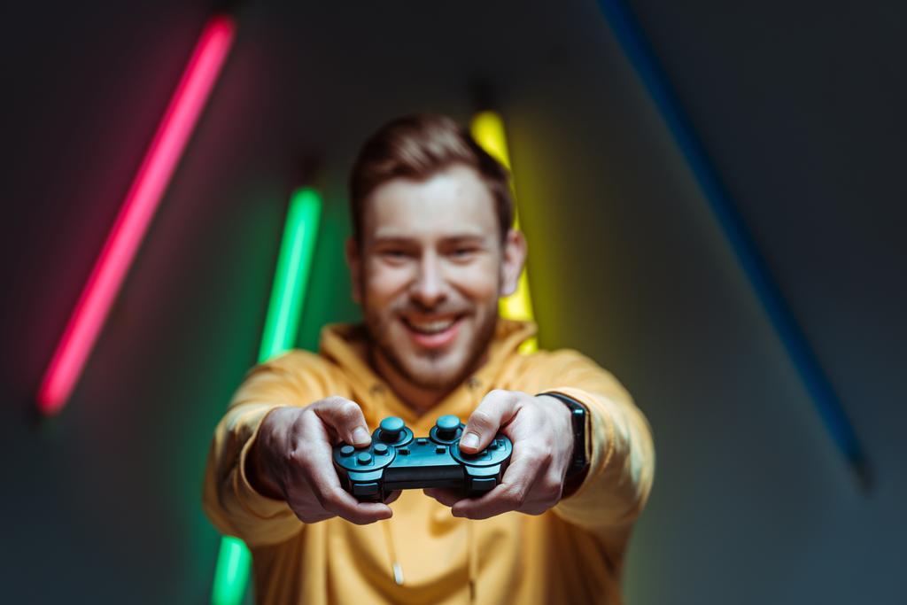 selektywne skupienie przystojnego i uśmiechniętego człowieka trzymający Gamepad  - Zdjęcie, obraz