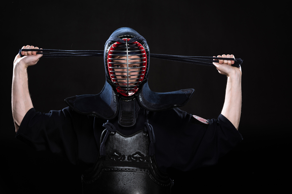 Kendo fighter in armor tying helmet on black - Photo, Image