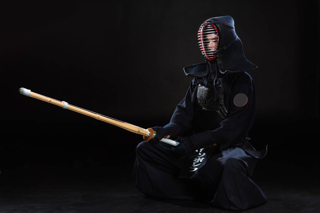 Kendo combattente in casco in possesso di spada di bambù su nero
 - Foto, immagini