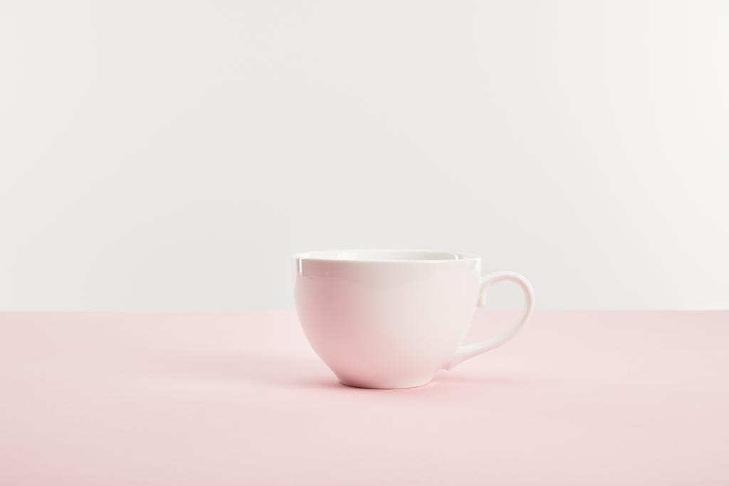 taza blanca con bebida en la superficie rosa aislado en gris
  - Foto, imagen
