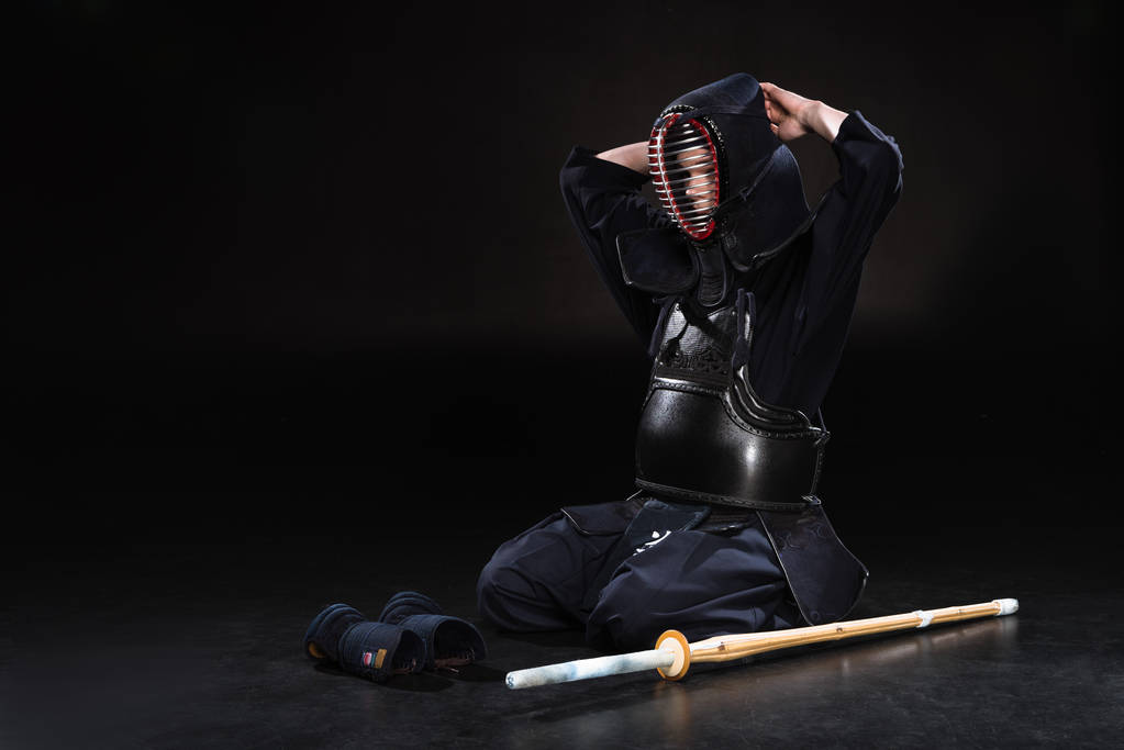Combattant Kendo assis sur le sol et enlever le casque sur noir
 - Photo, image