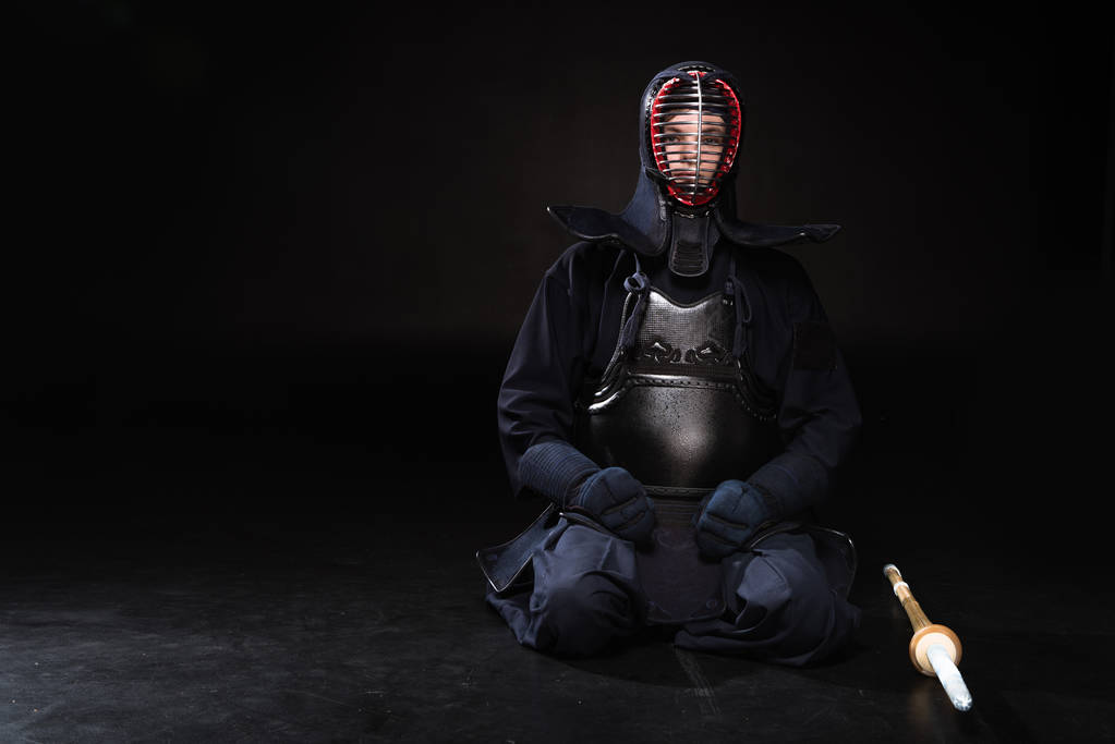 Кендо винищувач в шолом з бамбука меч, сидячи на чорному - Фото, зображення