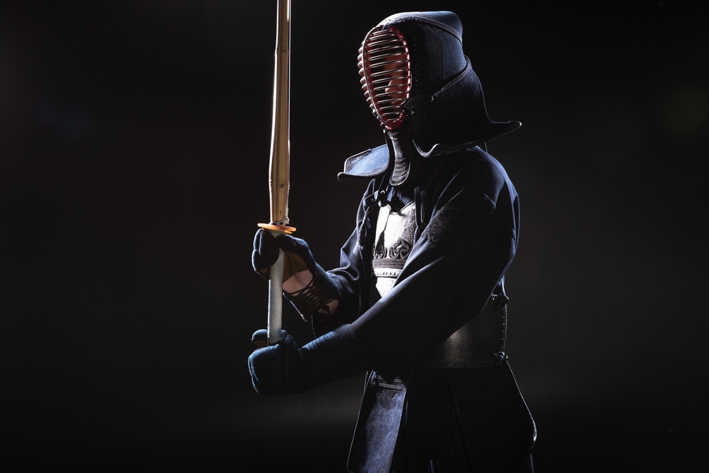 Combatiente Kendo en casco sosteniendo espada de bambú sobre negro
 - Foto, imagen