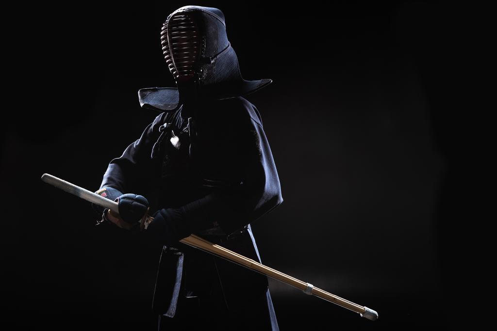 Kendo lutador no capacete segurando espada de bambu em preto
 - Foto, Imagem