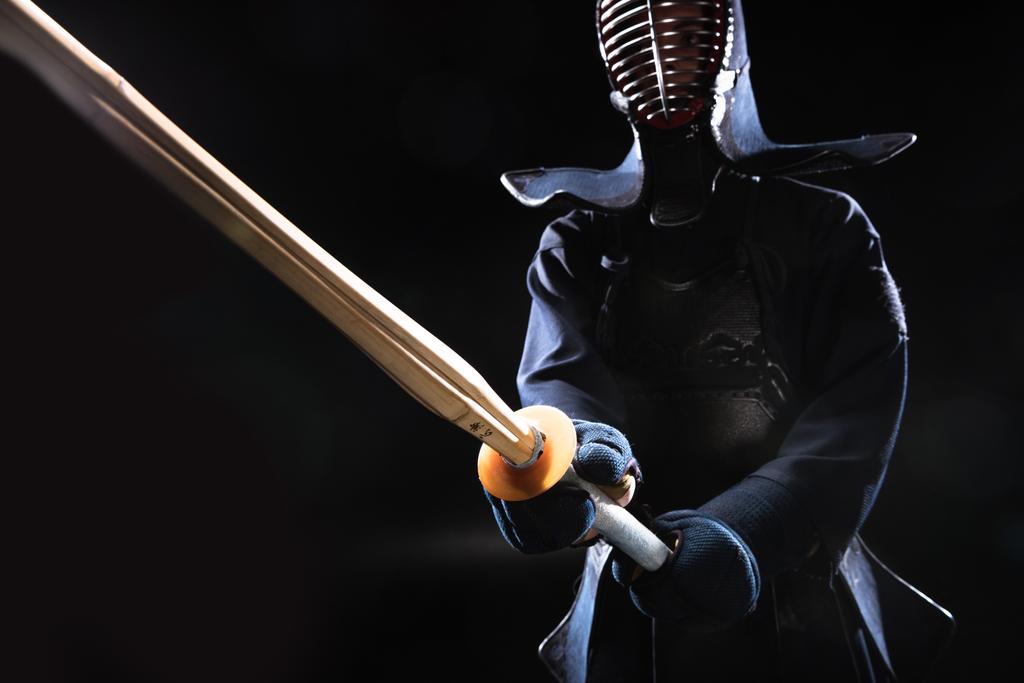 Kendo-Kämpfer im Helm mit Bambusschwert auf schwarz - Foto, Bild