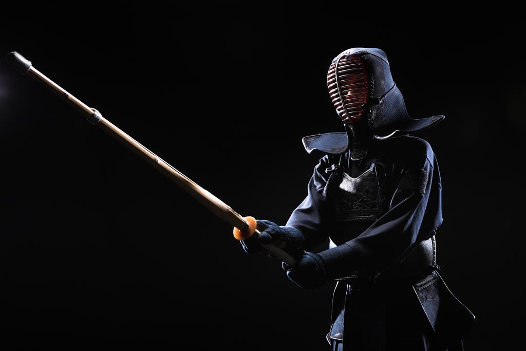 Combattant Kendo en armure pratiquant avec épée de bambou isolé sur noir
 - Photo, image