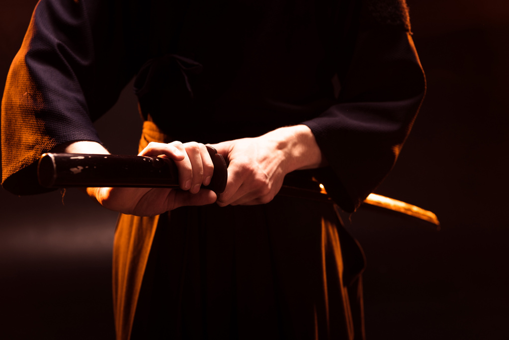 Partial view of kendo fighter holding bambo sword on black - Photo, Image