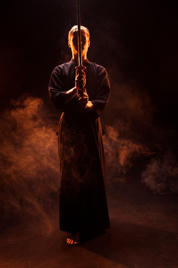 煙で剣道の剣を持った着物姿の若い男の完全な長さのビュー - 写真・画像