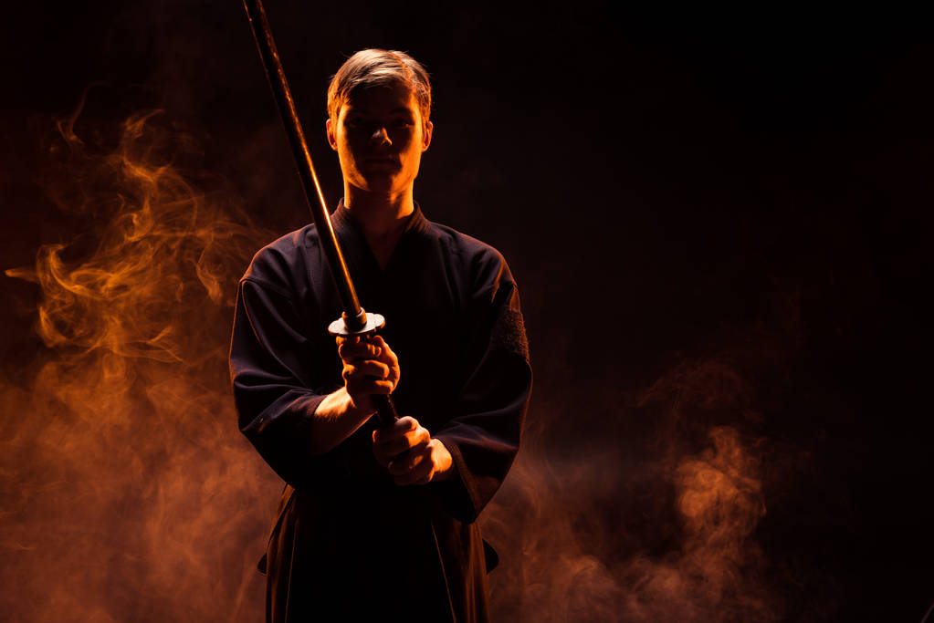 Jovem em quimono segurando espada kendo em fumaça
 - Foto, Imagem