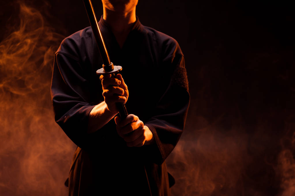 Przycięte widzenia młodego człowieka w kimono, trzymając miecz do kendo w dym - Zdjęcie, obraz
