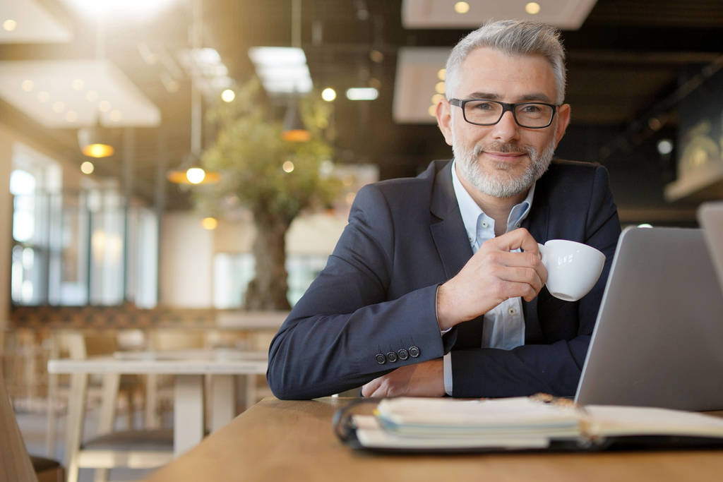 Homem de negócios maduro sorrindo para a câmera durante o trabalho coffee break
 - Foto, Imagem