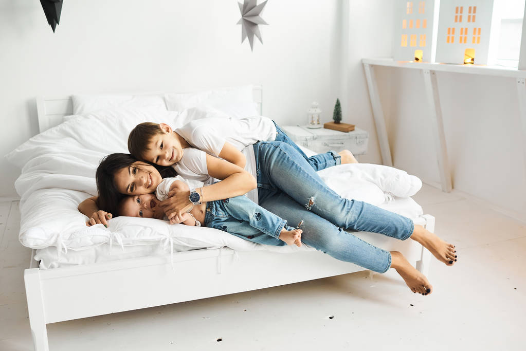 щаслива любляча сім'я. мати грає зі своїми дітьми в ліжку
 - Фото, зображення