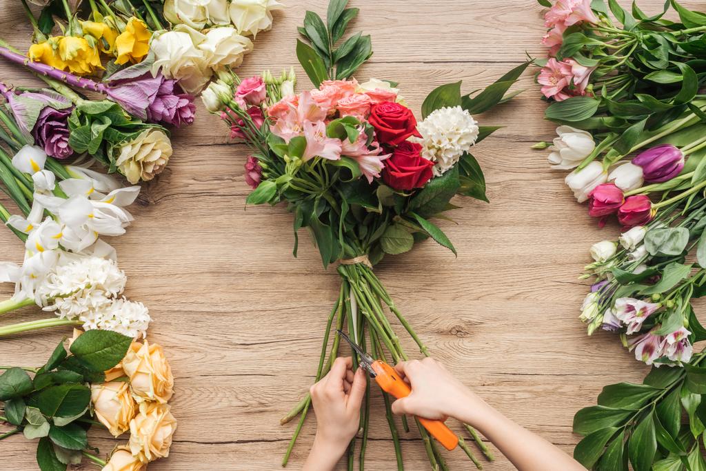Teilansicht Blumenhändler schneidet Blütenstiele auf Holzoberfläche - Foto, Bild