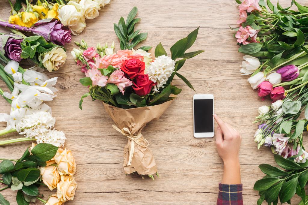 Kısmi Çiçekçi Çiçek ahşap yüzeyde yakınındaki boş ekran ile smartphone kullanarak görünümünü - Fotoğraf, Görsel