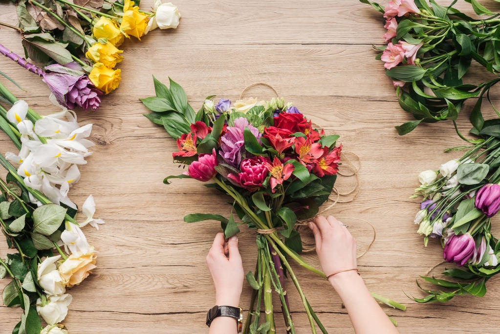 zugeschnittene Ansicht des Floristen, der Blumenstrauß auf Holzoberfläche herstellt - Foto, Bild