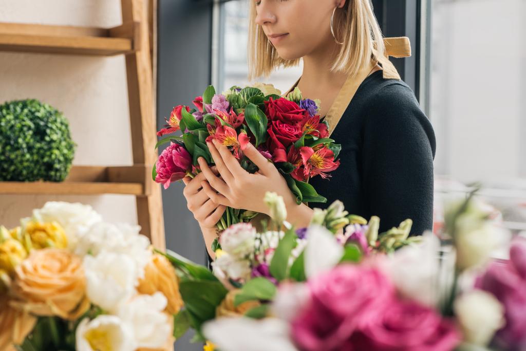 Vue recadrée du fleuriste en tablier tenant bouquet dans la boutique de fleurs
 - Photo, image