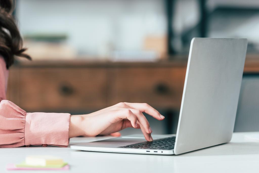 Cropped view of girl in pink shirt typing on laptop keyboard - Photo, Image