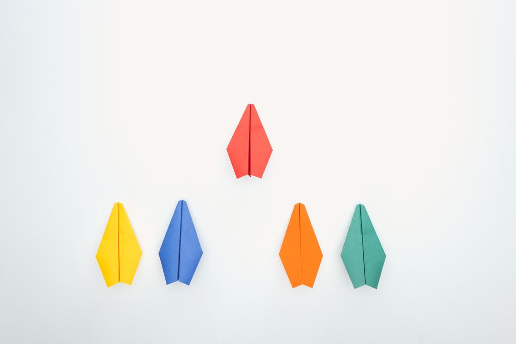 Tasainen lay värikkäitä paperin lentokoneita valkoisella pinnalla
 - Valokuva, kuva