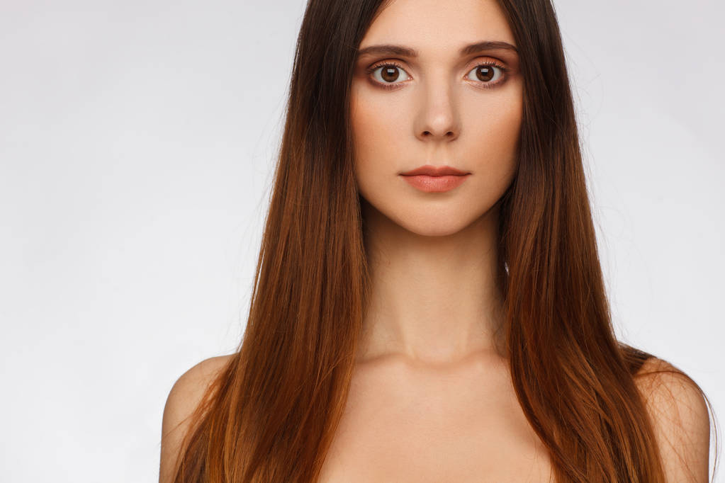 Porträt einer schönen Frau mit glatten langen Haaren und interessanten Emotionen. hellgrauer Hintergrund - Foto, Bild
