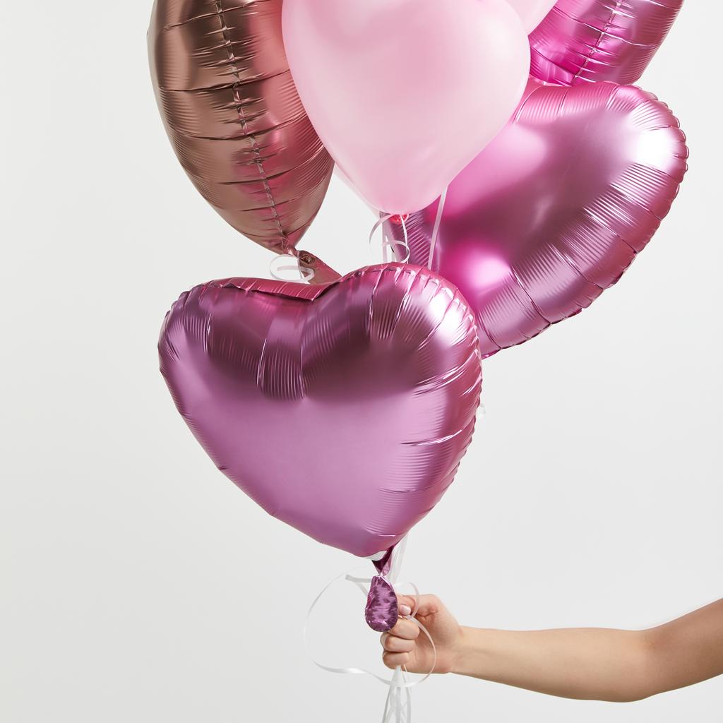 vista parcial de la niña sosteniendo globos de aire rosa en forma de corazón aislados en blanco
 - Foto, imagen