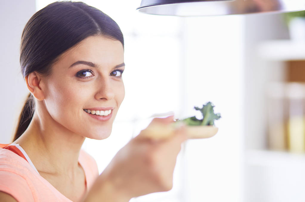 Usmívající se mladá žena míchající čerstvý salát v kuchyni. - Fotografie, Obrázek