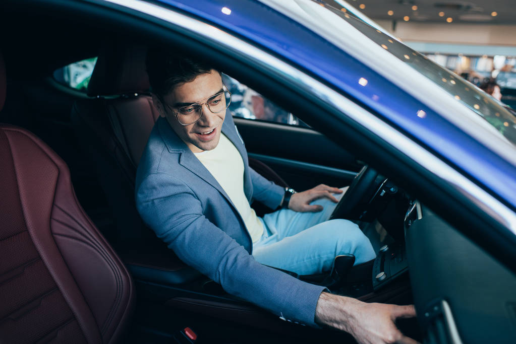επιλεκτική εστίαση του επιτυχημένου ευτυχισμένο άνθρωπο σε γυαλιά που κάθονται στο αυτοκίνητο  - Φωτογραφία, εικόνα