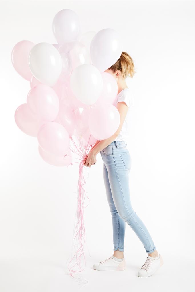 Tyttö rento vaatteet kattaa kasvot vaaleanpunainen ilmapalloja eristetty valkoinen
 - Valokuva, kuva