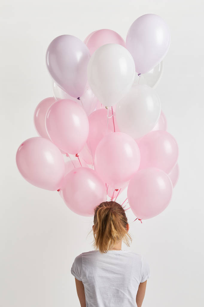 vista posterior de la niña sosteniendo globos de aire rosa aislados en blanco
 - Foto, Imagen