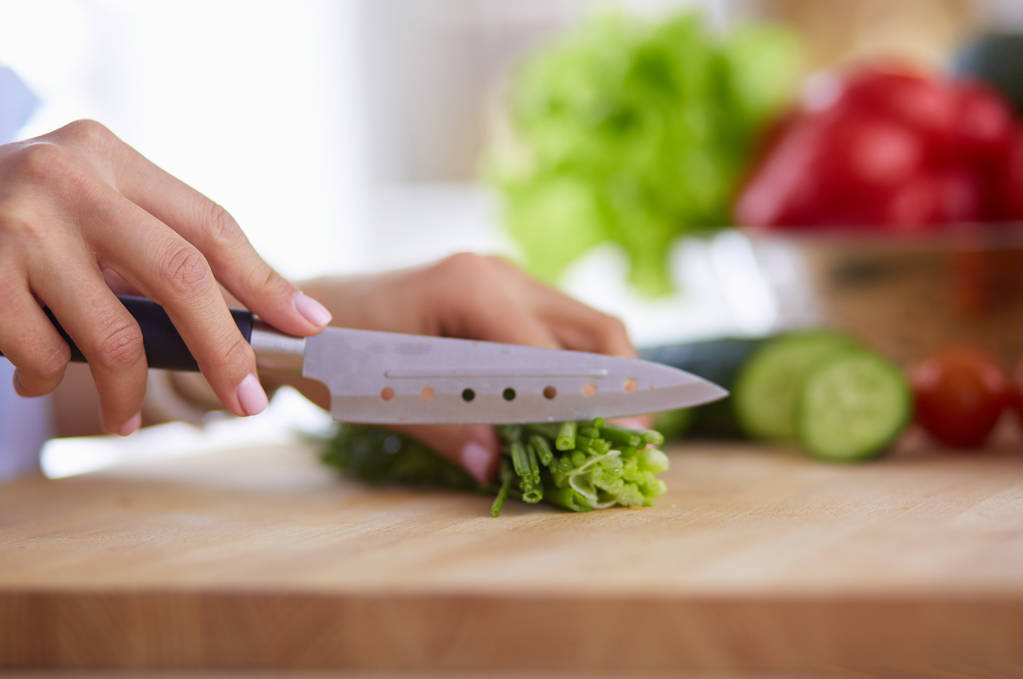 Mujer joven cortando verduras en la cocina en casa. - Foto, imagen
