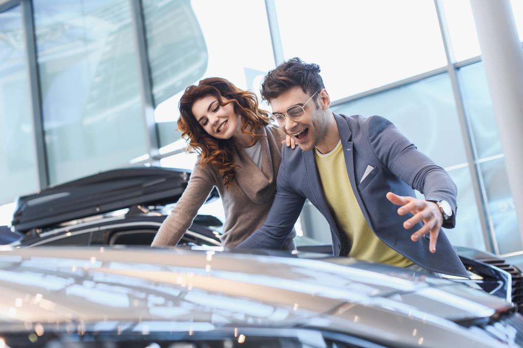 selective focus of happy man and girl smiling while looking at car  - Photo, Image