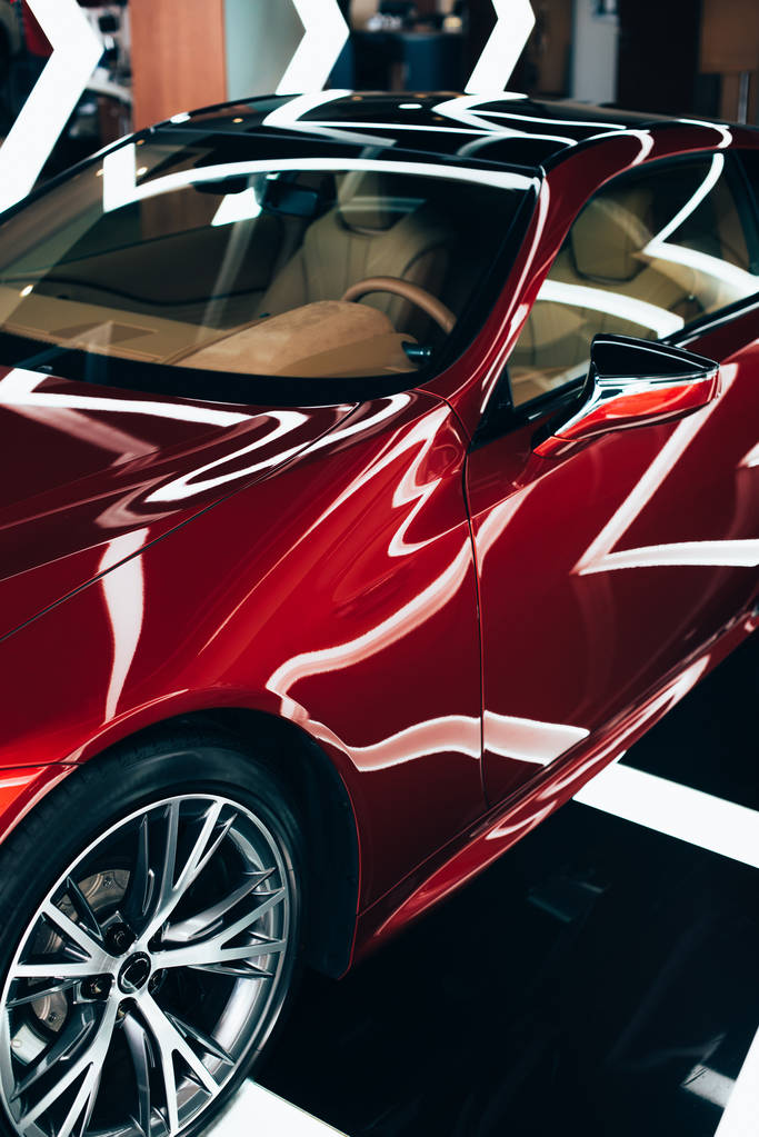 nuevo automóvil rojo y brillante con rueda metálica en la sala de exposición del coche
  - Foto, Imagen