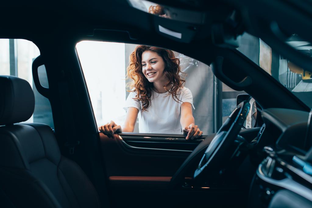 foco seletivo de mulher encaracolada alegre em pé perto do automóvel
  - Foto, Imagem