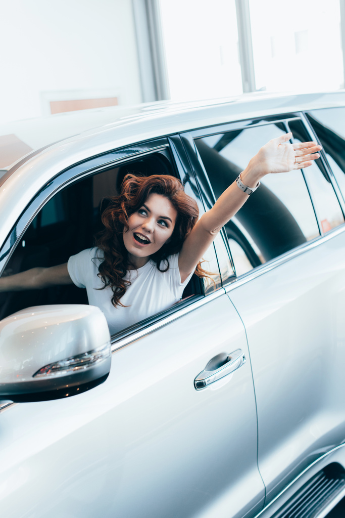 enfoque selectivo de mujer rizada excitada gritando mientras agita la mano en el automóvil
  - Foto, imagen