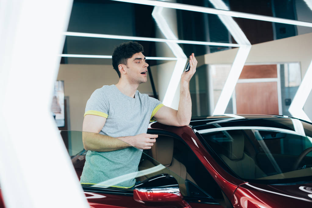 enfoque selectivo de hombre feliz sosteniendo las llaves del coche mientras está de pie cerca de coche nuevo
 - Foto, Imagen